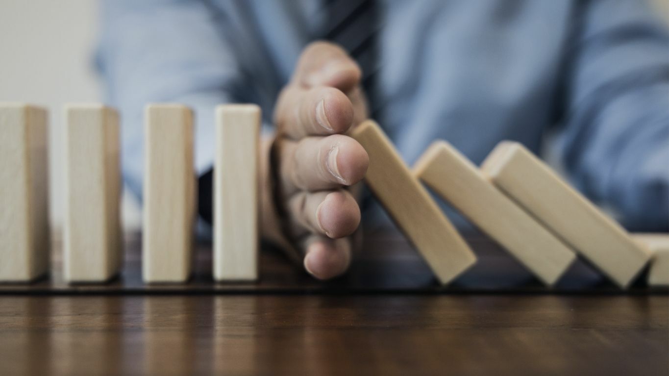 Hand unterbricht eine fallende Reihe von Dominosteinen
